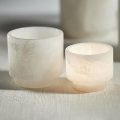 two white candles sitting next to each other on a table