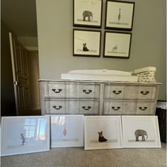 there are four framed pictures on the floor next to an old dresser and crib