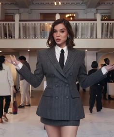 a woman wearing a suit and tie standing in a lobby