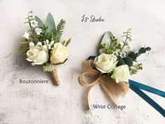 two boutonnieres with white roses and greenery tied to them on the ground