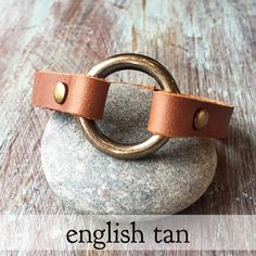 the english tan leather bracelet is on top of a rock