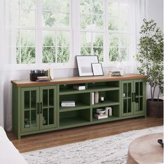 a living room scene with focus on the entertainment center and window in the back ground