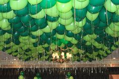 many green balloons are hanging from the ceiling