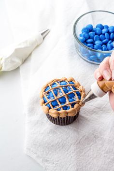 someone is decorating a cupcake with blue candies