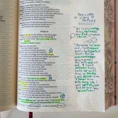 an open book with writing on the pages and handwritten words in green, red, and blue