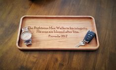 a wooden tray with two watches and a keychain on it that says, the righteous man walks in his integrity