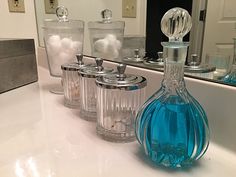 a bathroom counter topped with blue glass bottles and jars filled with white balls in front of a mirror