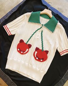 a white sweater with red and green appliques on it