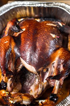 a roasted turkey in a foil pan with olives