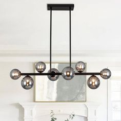 a modern chandelier hangs over a dining room table and chairs in front of a fireplace