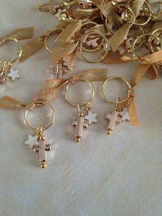 a bunch of gold and white cross charms sitting on top of a table next to each other