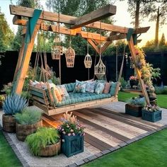 a wooden swing bed sitting in the middle of a lush green yard with hanging planters and potted plants