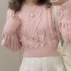 a woman wearing a pink sweater and white pants holding a cell phone up to her ear