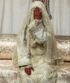 a woman in a white wedding dress sitting on a couch with her hands covering her face