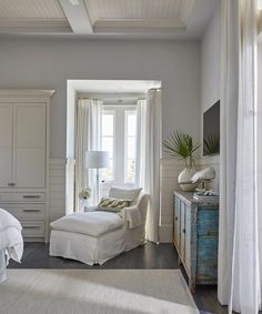 a bedroom with white furniture and large windows