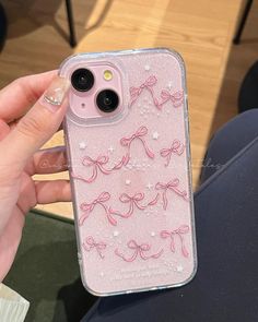 a person holding up a pink iphone case with bows on the front and back cover