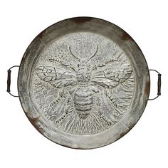 a metal plate with a bee design on the front and sides, sitting on a white background