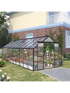 a small greenhouse with plants in it and flowers growing inside the house on the lawn