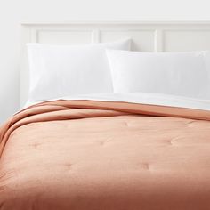 a bed with white pillows and an orange blanket