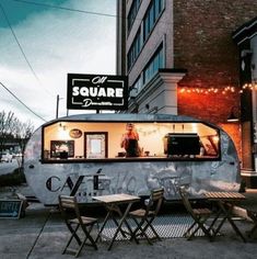 the food truck is parked on the side of the road with tables and chairs around it