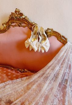 a woman laying on top of a bed in a white dress and gold headboard