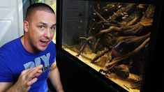 a man sitting in front of an aquarium looking surprised