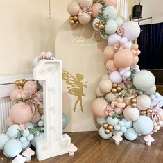 a balloon arch is decorated with pastel colors