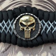 a bracelet with a gold skull on it and black braiding around the clasps