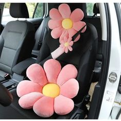 two pink flowers are placed on the back of a car seat in front of another flower