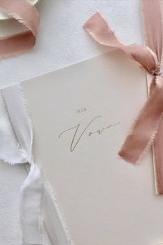 This vow book is in beige cardstock paper with golden foil calligraphy and typeface, as well as pink and white ribbons decorating the piece. Scrapbook Items