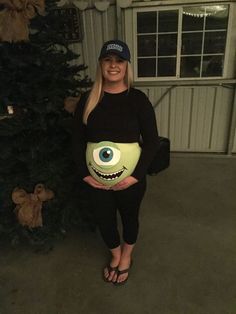 a woman in black shirt and hat standing next to christmas tree with fake eyes on it