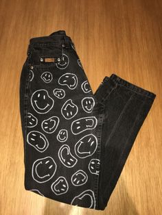 a pair of black jeans with smiley faces on them sitting on top of a wooden floor