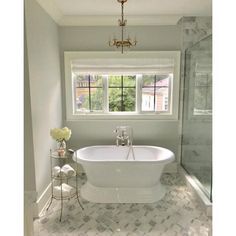 a white bath tub sitting under a window in a bathroom