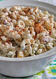 a white bowl filled with macaroni salad on top of a colorful table cloth