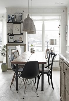 a dining room table with chairs and pictures on the wall behind it in front of a window