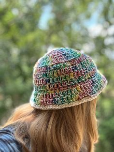 a woman wearing a crocheted hat with trees in the backgrouund