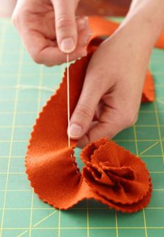 someone is cutting fabric with a pair of scissors to make a flower ornament