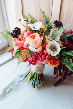 a bouquet of flowers sitting on top of a white cloth covered floor next to a wooden door