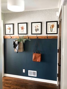 a blue wall with three pictures on the wall and a purse hanging from it's hooks