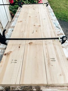 a long wooden table with two black handles on it's end and some flowers in the background