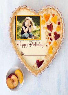 a heart shaped cake with a photo on it and some fruit in the bowl next to it