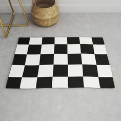 a black and white checkered rug on the floor next to a basket with a plant