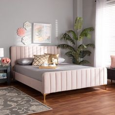 a bedroom with a pink bed and two side tables in front of the window,