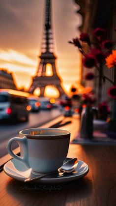 a cup and saucer sitting on a table in front of the eiffel tower