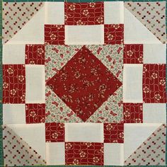 a red and white quilted square with flowers on the center is featured in this close up photo