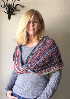 a woman standing next to a wall with a knitted shawl on her shoulders