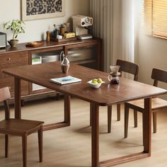 a wooden table with two chairs and a bowl of fruit on the table next to it