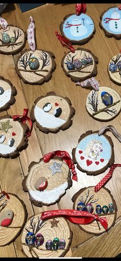 wooden slices with ornaments on them sitting on a wood table next to a red ribbon