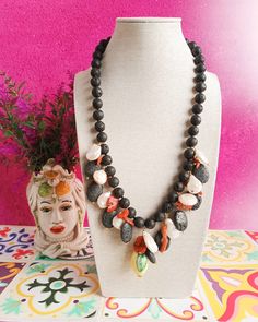 Sicilian style, handknotted necklace made of: - Lava rock (10 mm), black color; - Sicilian ceramic Lemon (35 mm x 22 mm); - Lava rock, coin shape, black color; - Baroque Pearls (12 mm), white color; - Red Coral braches; - Gold plated 925 Sterling Silver Carabiner. Total lenght : 43,5 cm / 17,13 inches * SHIPPING * Your order will be shipped within 1-3 business days from your purchase. You can choose between 2 shipping methods: STANDARD SHIPPING (without tracking) or REGISTERED MAIL (with trackin Lava Stone Necklace With Natural Stones For Gift, Lava Stone Jewelry With Round Natural Stones, Black Lava Stone Necklace Spiritual Style, Bohemian Black Lava Stone Jewelry, Lava Rock Necklace, Lava Stone Necklace, Lava Rock, Bib Necklaces, Lava Stone