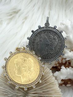 two coin pendants sitting next to each other on top of a pile of white fur